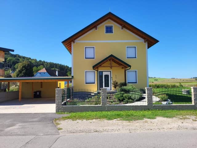 Strassenansicht des Hauses mit Vorgarten, Schmuckzaun und Carport