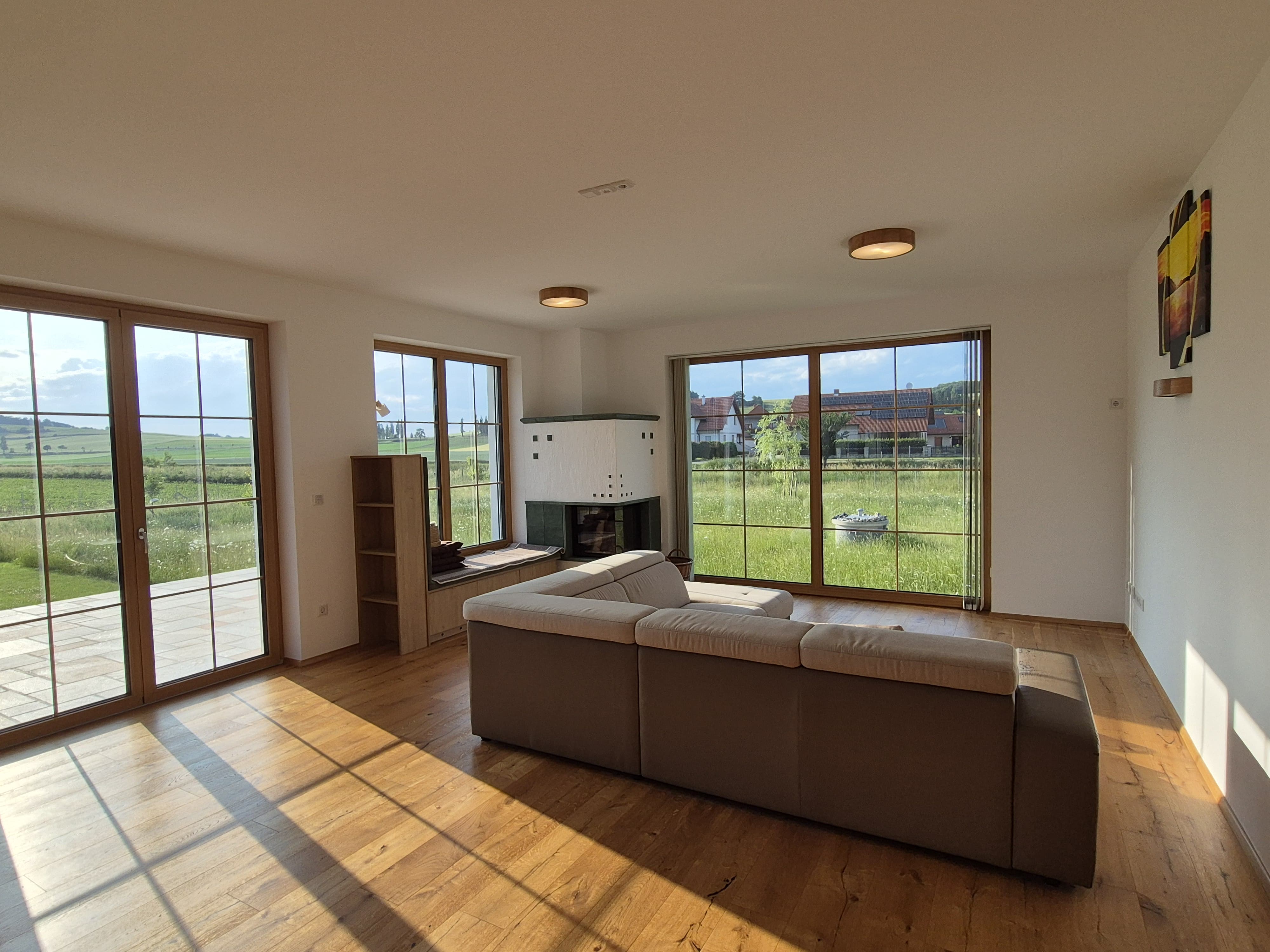 Offener Wohnbereich mit Eichenparkett, Kachelkamin und Blick in den Garten